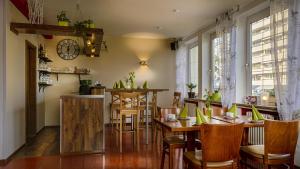 ランツフートにあるHotel Luitpoldのテーブルと椅子、壁掛け時計のあるレストラン