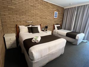 a hotel room with two beds and a brick wall at Warrina Motor Inn Wodonga CBD in Wodonga