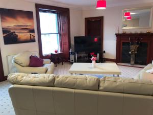 sala de estar con sofá y TV en Executive Serviced Apartments 1 en Forfar