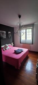 a bedroom with a pink bed and a chandelier at NALA HOUSE, acogedor,bien comunicado,aparcamiento gratis en la calle in Bilbao