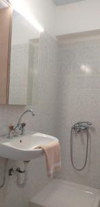 uma casa de banho branca com um lavatório e um chuveiro em Ammos Apartments em Agios Nikolaos