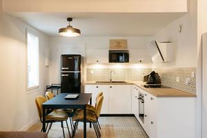 a kitchen with a table and a black refrigerator at Le Clos des Vignes in Pauillac