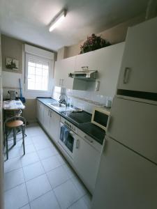 uma cozinha com electrodomésticos brancos e uma mesa em NALA HOUSE, acogedor,bien comunicado,aparcamiento gratis en la calle em Bilbao