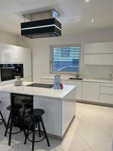 a kitchen with white cabinets and a island with stools at Luxus Villa Hannover Messe in Hannover