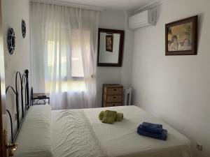 a bedroom with a bed with white sheets and a window at Turismo Vacacional de Lujo ttluga -Málaga in Cala del Moral