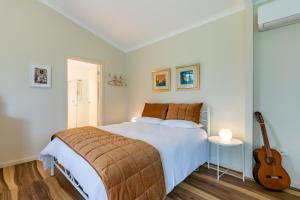 a bedroom with a large bed and a guitar at Meander Retreat - Garden Studio in Springton
