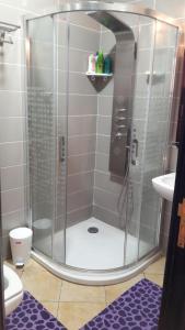 La salle de bains est pourvue d'une douche avec une porte en verre. dans l'établissement Lilacs Garden Cabo Negro Piscines WiFi -only family, à Cabo Negro