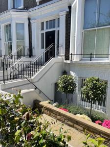 Una casa blanca con escaleras y plantas delante. en Stylish 3-bedroom flat in Kensington, en Londres