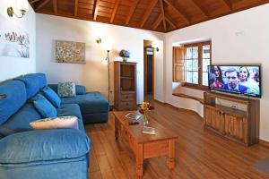 a living room with a blue couch and a tv at Casa El Vendaval in Tijarafe