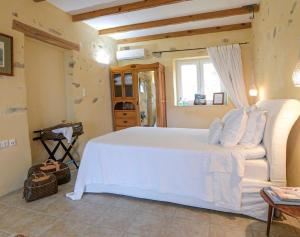 ein Schlafzimmer mit einem weißen Bett und einem Fenster in der Unterkunft Olive Hill in Elevtheraí