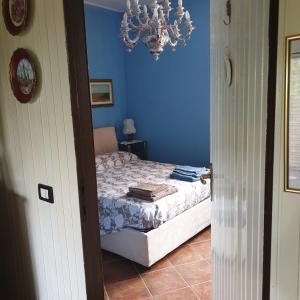 una camera da letto con un letto con pareti blu e un lampadario a braccio di B&B Villa Giardini Susanna a Gattico