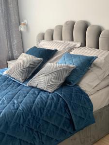 Una cama con edredón azul y almohadas encima. en Platinum De Lux Apartament, en Stargard