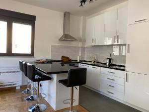 una cocina con armarios blancos y encimeras negras en Amfora Suite, en Trebinje