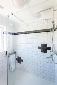 a white tiled bathroom with a glass shower stall at Newly renovated 2 bed house with large garden. in Phillack