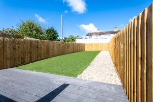 a wooden fence with a green lawn behind it at Newly renovated 2 bed house with large garden. in Phillack