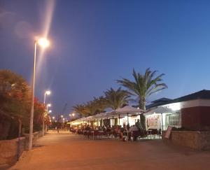プエルト・デ・サグントにあるFriendly home Bella casaの夜のテーブルとパラソルとヤシの木のある通り