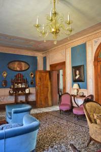una sala de estar con sillas azules y rosas y una lámpara de araña. en Palazzetto Scodellari en San Vito al Tagliamento