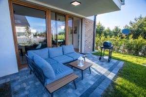 a patio with a blue couch and a table at Dom na wzgórzu z widokiem na morze etezje in Mechelinki