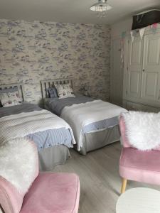 um quarto com 2 camas e uma cadeira rosa em Coastal Joy - Family and friends bedrooms em Newbiggin-by-the-Sea