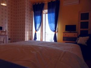a bedroom with a bed with blue curtains and a window at Leucosia Bed & Breakfast in Salerno