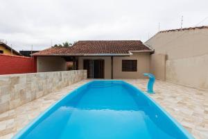 una gran piscina azul frente a una casa en Casa até 13 pessoas, Praia de Gaivotas, Itanhaém, piscina,300MB WiFi, churrasqueira, en Itanhaém