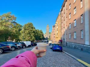 a person holding a cup of coffee on a city street at Beautiful design studio in the heart of Kallio in Helsinki