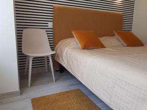 1 dormitorio con 1 cama y 1 silla blanca en COTE JARDIN - CANCALE - GITE STANDING - PROCHE CENTRE ET PORT, en Cancale