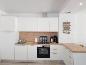 een keuken met witte kasten en een zwarte oven bij COTE JARDIN - CANCALE - GITE STANDING - PROCHE CENTRE ET PORT in Cancale