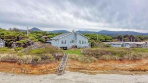 una casa blu sulla spiaggia con una scala di Payn House a Yachats