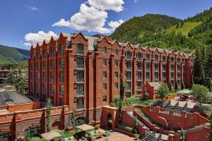 un grande edificio in mattoni rossi di fronte a una montagna di Aspen St Regis Resort Hotel Room With 2 Queens ad Aspen