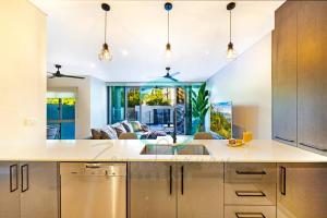 een keuken en een woonkamer met een bank bij ZEN ARCTIC Luxury 2-Story T/House + Pool & Markets in Fannie Bay