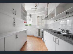 a white kitchen with white cabinets and a sink at Richmond Private Rooms - 151 Hoddle Homestay in Melbourne