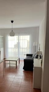 sala de estar con sofá negro y mesa en Apartamento Ophelia, en Puerto del Rosario