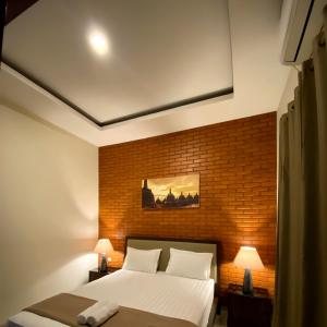 a bedroom with a bed and a brick wall at Omah Watu Homestay in Jetis