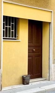 een geel gebouw met een bruine deur en een mand bij La Maiolica Blu in Trapani