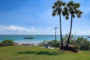 two palm trees in a park next to the ocean at ZEN SEA BREEZE - Darwin's Premier Family Apt in Darwin