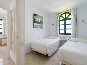 two beds in a white room with a window at Marina nº 53 in Puerto de Mogán