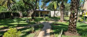 un jardín con palmeras y una pasarela en Gästehaus Diani en Diani Beach