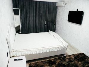 Cama blanca en habitación con TV en Квартира однокомнатная VIP, en Uralsk