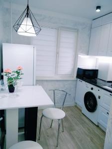 Квартира однокомнатная VIP في أورالسك: مطبخ مع طاولة بيضاء وكراسي وغسالة ملابس