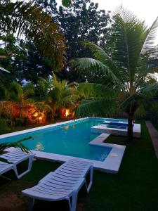 a swimming pool with two lounge chairs and a palm tree at The old normal private residences in Panglao