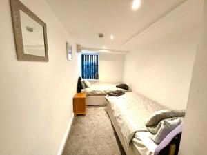 a small room with two beds and a window at Llewellyn Avenue Apartment in Llandudno