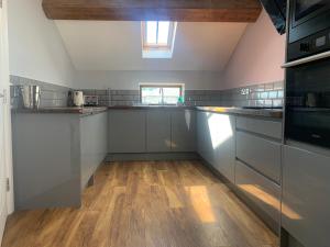 a kitchen with white cabinets and a wooden floor at Cosy 2 Bed Apartment in central Kirkby Lonsdale in Kirkby Lonsdale +15 photos