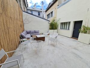 een patio met een bank, stoelen en een tafel bij Le Saint Christophe - Mairie d'Aubervilliers ligne 12 in Aubervilliers