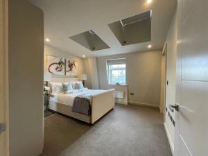 ein Schlafzimmer mit einem weißen Bett und einem Fenster in der Unterkunft luxurious, 2 bed, 2 bath penthouse apartment in highly desirable Chigwell CHCL F8 in Chigwell