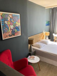 une chambre d'hôtel avec un lit et un fauteuil rouge dans l'établissement R.I.O. PASSIONS, à Toulon