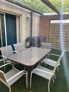 Une table à manger et des chaises sont disponibles sur la terrasse. dans l'établissement Cottage Chaleureux tout équipé climatisé à Jacou, à Montpellier