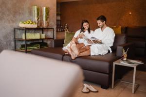 a man and woman sitting on a couch with a baby at Aktiv Hotel Edelweiss in Resia