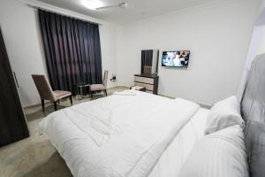 1 dormitorio con 1 cama blanca grande y TV en نسائم صلاله NassayemSalalah, en Salalah