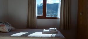 1 dormitorio con ventana y toallas en la cama en Aparts Complejo Ricanor en El Chaltén